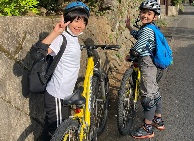 自転車を停めてピースサインをする子供たち